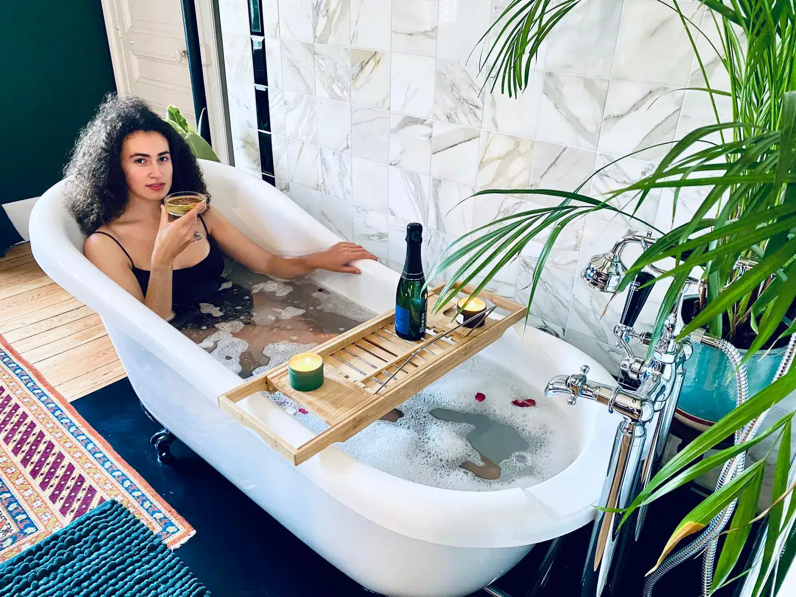 Personne dans baignoire avec coupe et bougie.