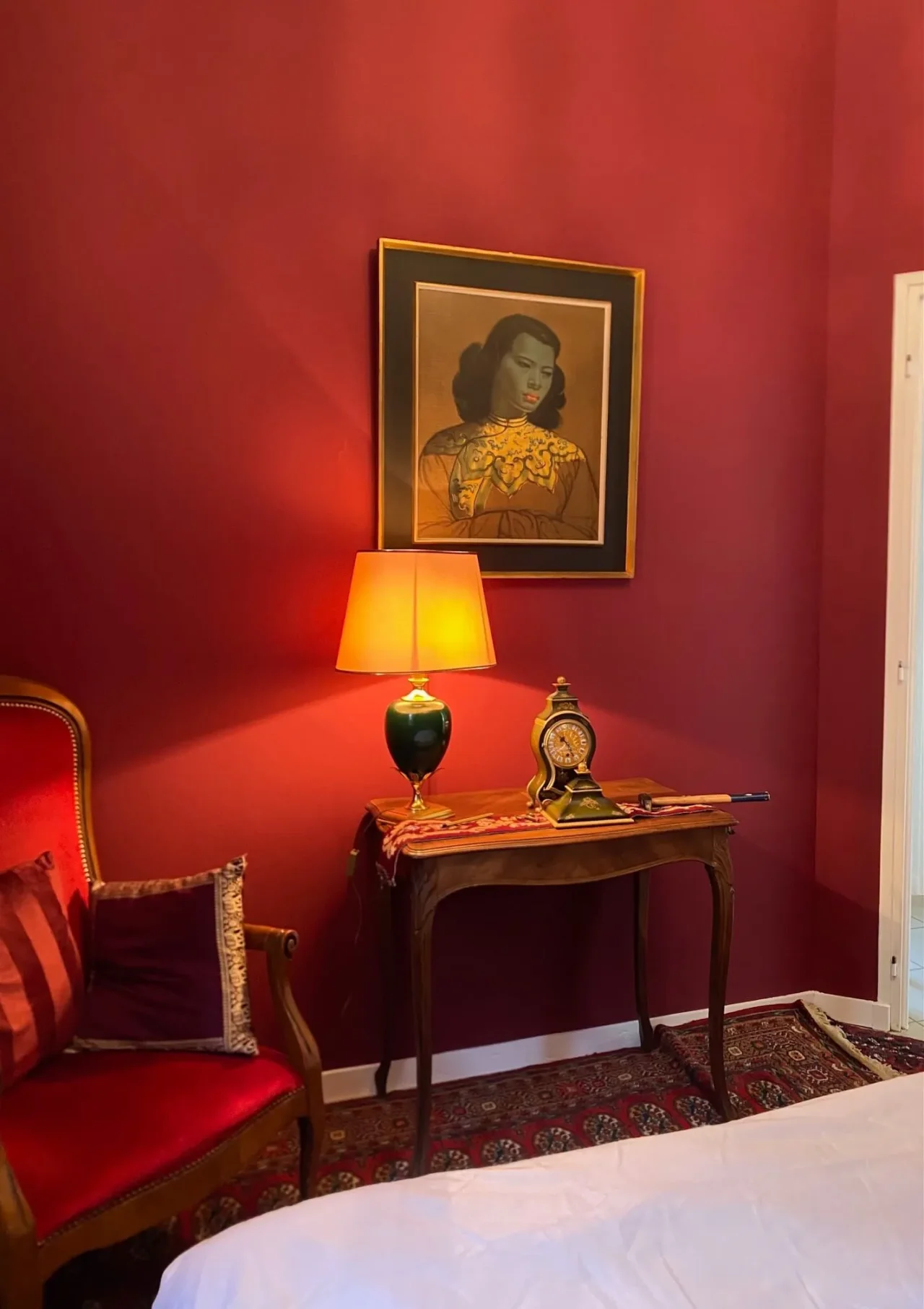 Console ancienne sous portrait sur mur rouge