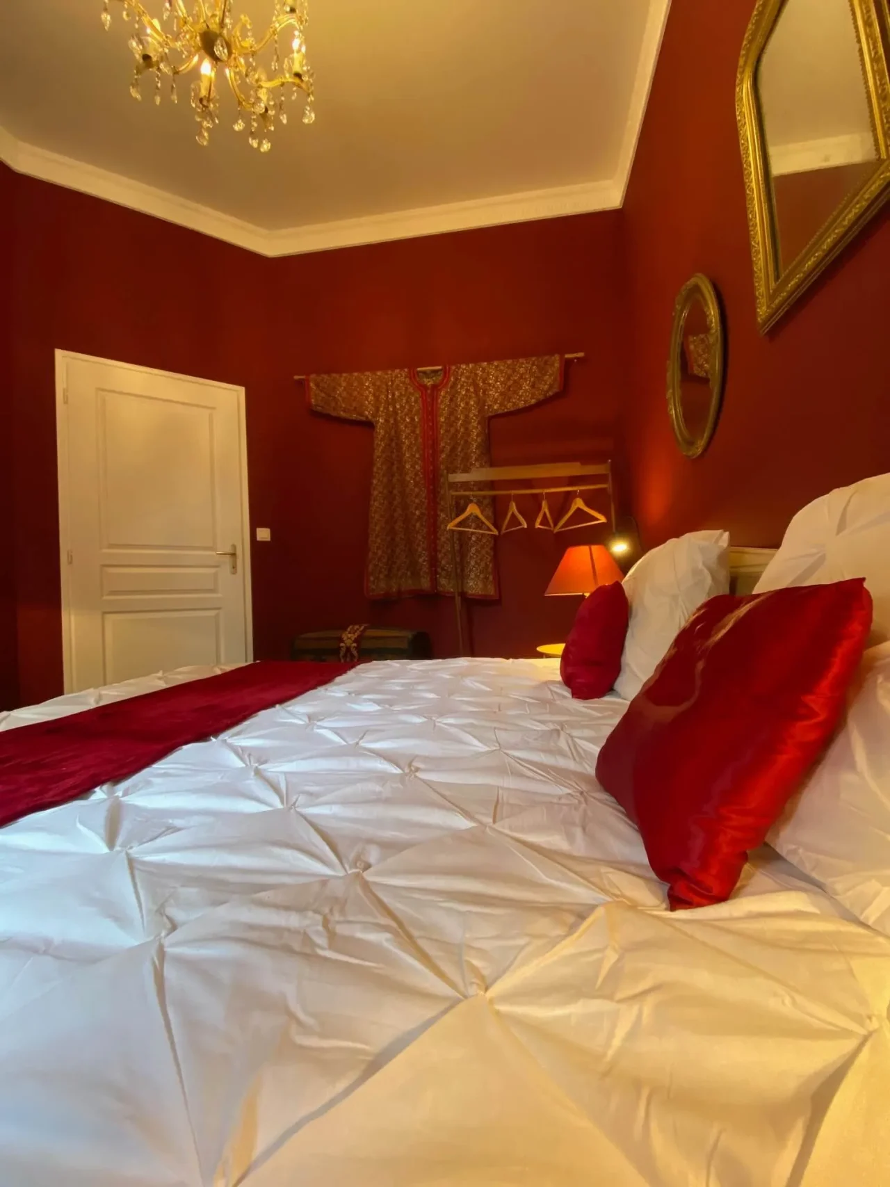Chambre élégante aux murs rouges et lit blanc