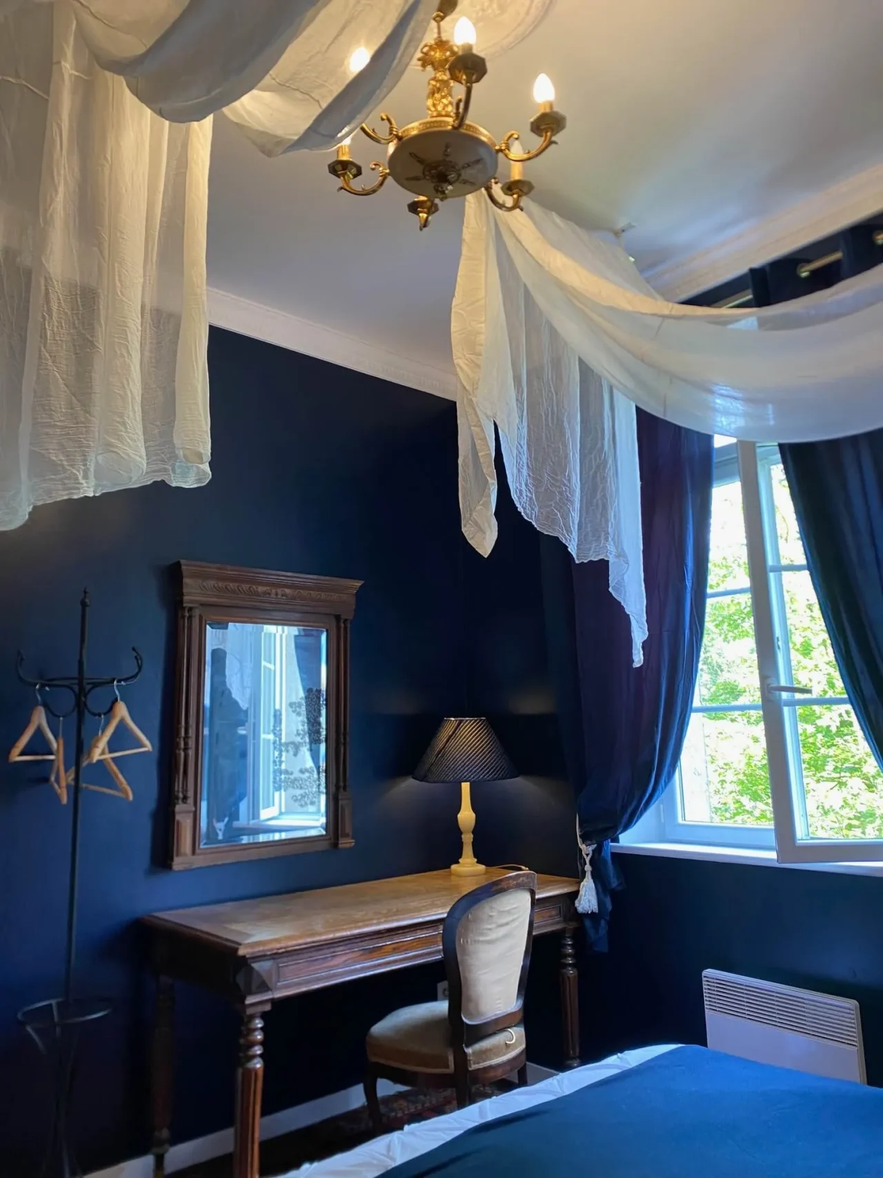 Chambre élégante aux murs bleus et baldaquin aérien